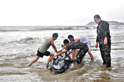 7月19日，受台风“威马逊”影响，一条虎头鲸受伤搁浅在广东阳江市海陵岛附近海域，武警边防官兵尝试着将鲸鱼送到深水区。