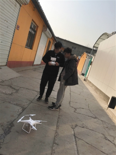 3月3日，朝阳区飞态创新店门前，一商家工作人员(左)向记者展示破解后的无人机被定位在太平洋上。