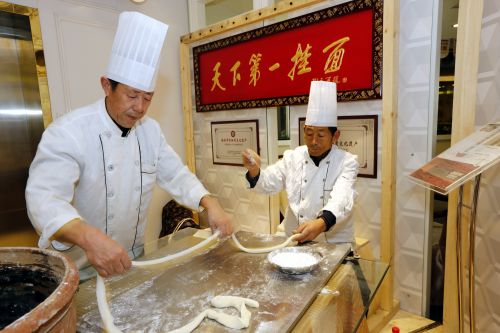张维贵右一和他的老搭档在西安上丰元中华面馆现场展示柳青故里吴堡手工挂面技艺