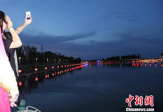 游客在游轮画舫上用手机自拍新疆克拉玛依夜景。　袁晶 摄