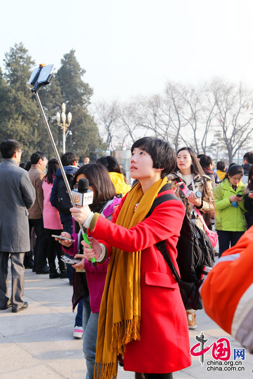 2015年两会，来自山东的一位红衣美女记者在人民大会堂前自拍留念。中国网 董宁 摄